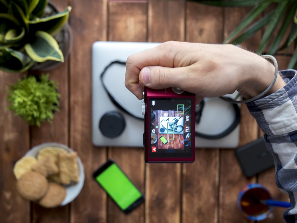 overhead photographer making photo with compact camera at home above the table